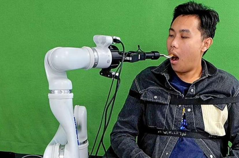 A robotic system developed by Cornell researchers feeds a student participant during a lab demonstration
