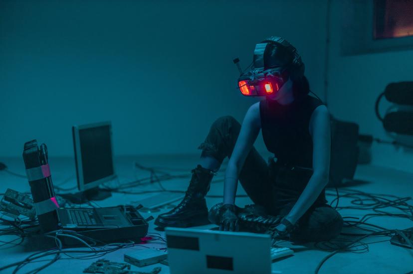 Person sat on floor using spatial computing headset and keyboard surrounded by other technology detritus