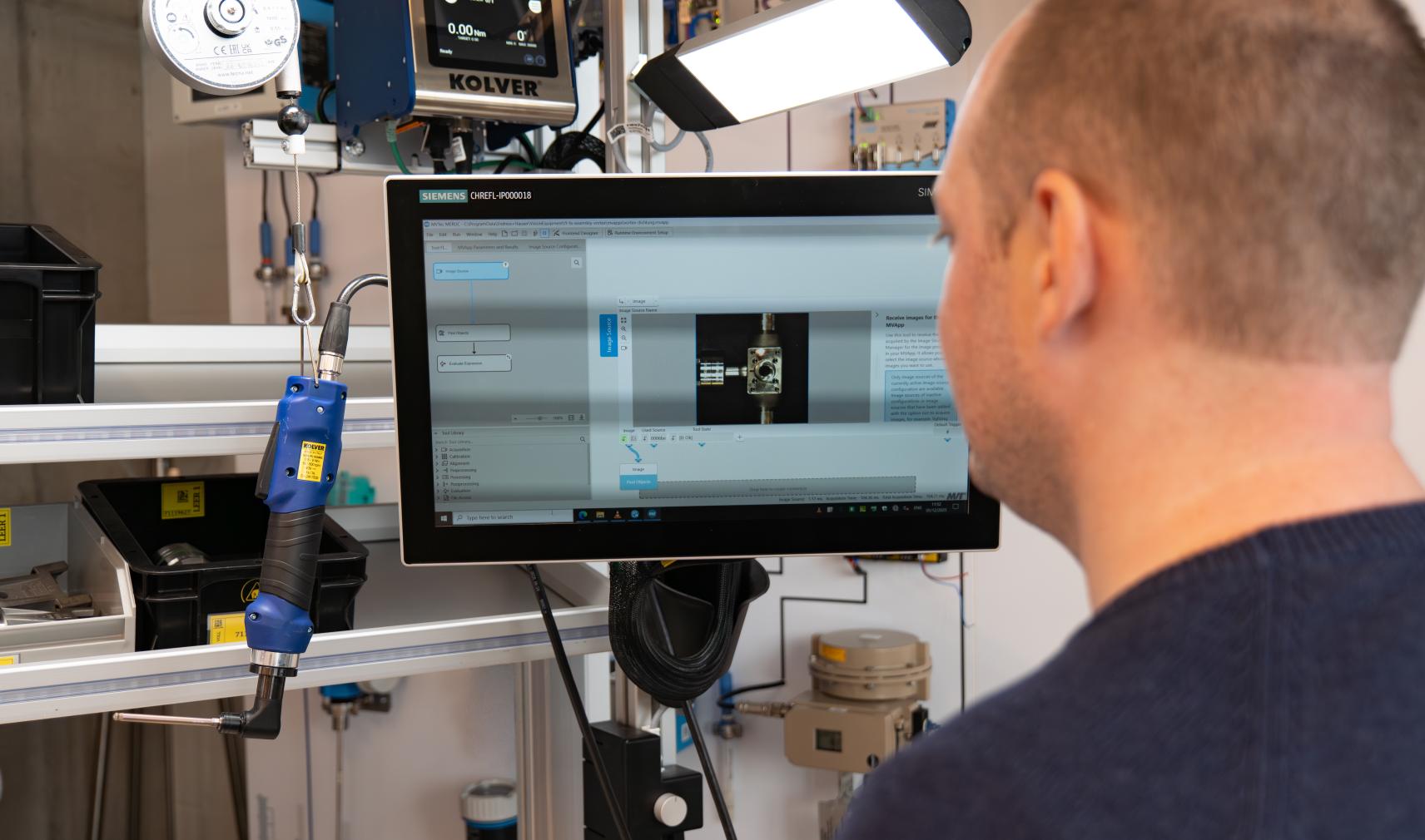 Manual assembly worker checks machine vision quality inspection system
