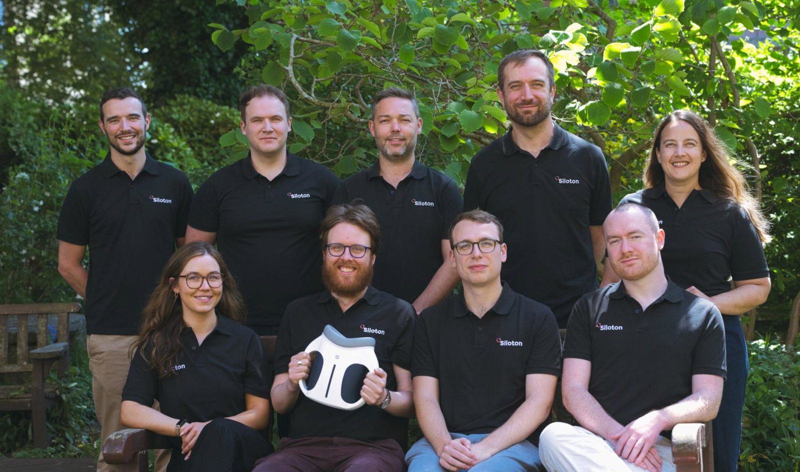 Employees sit outside and pose for a team photograph