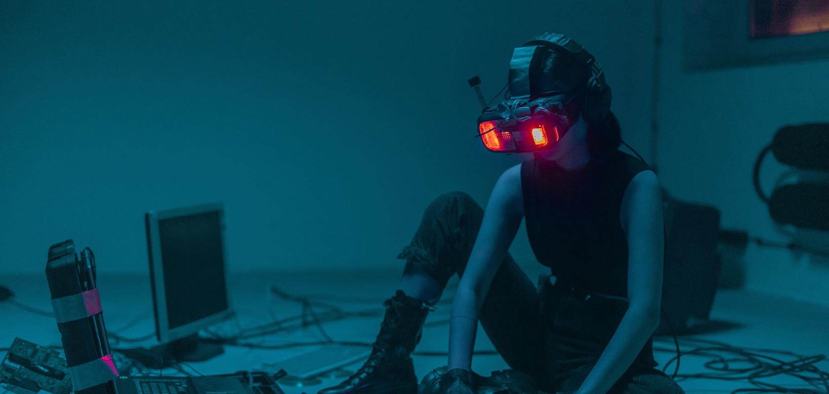 Person sat on floor using spatial computing headset and keyboard surrounded by other technology detritus