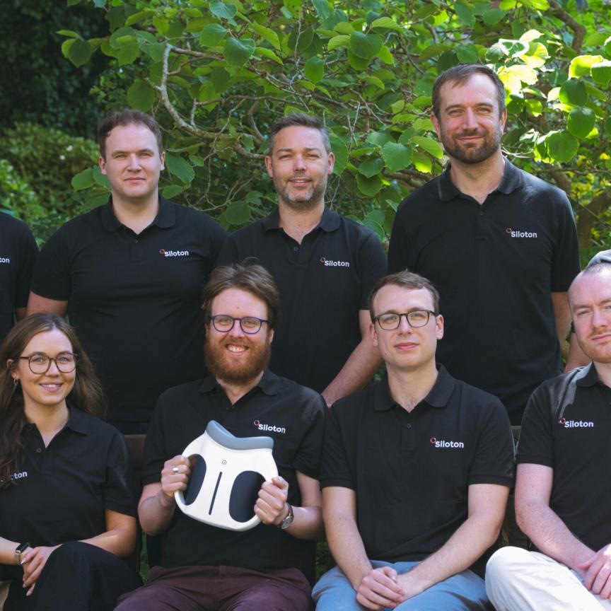 Employees sit outside and pose for a team photograph
